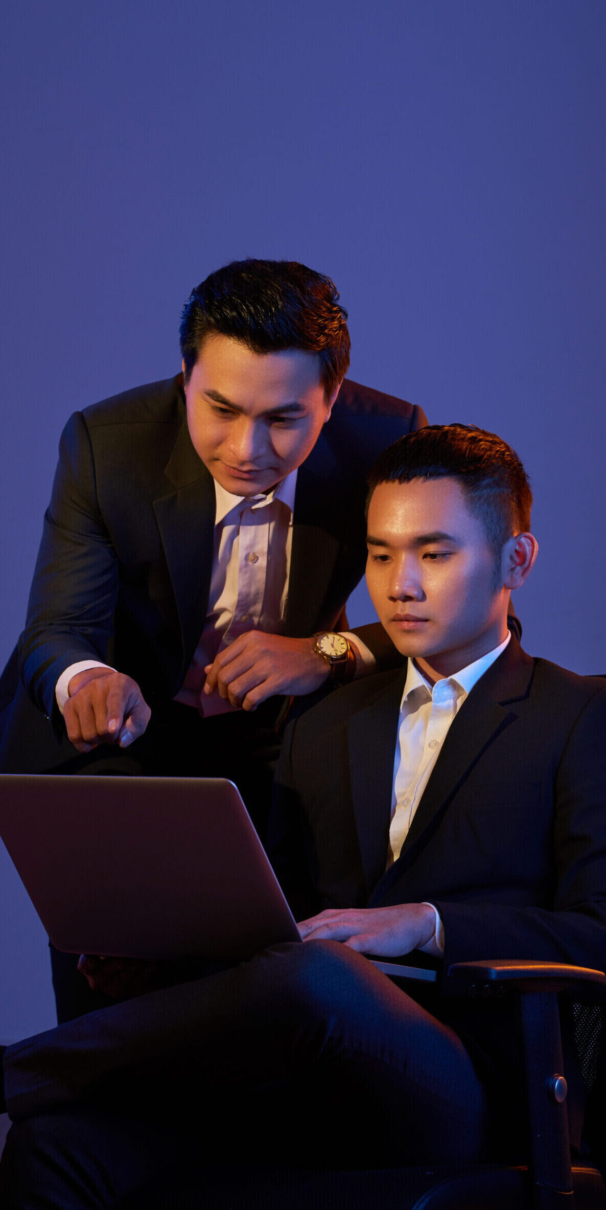 Young Vietnamese coworkers analyzing information on laptop screen