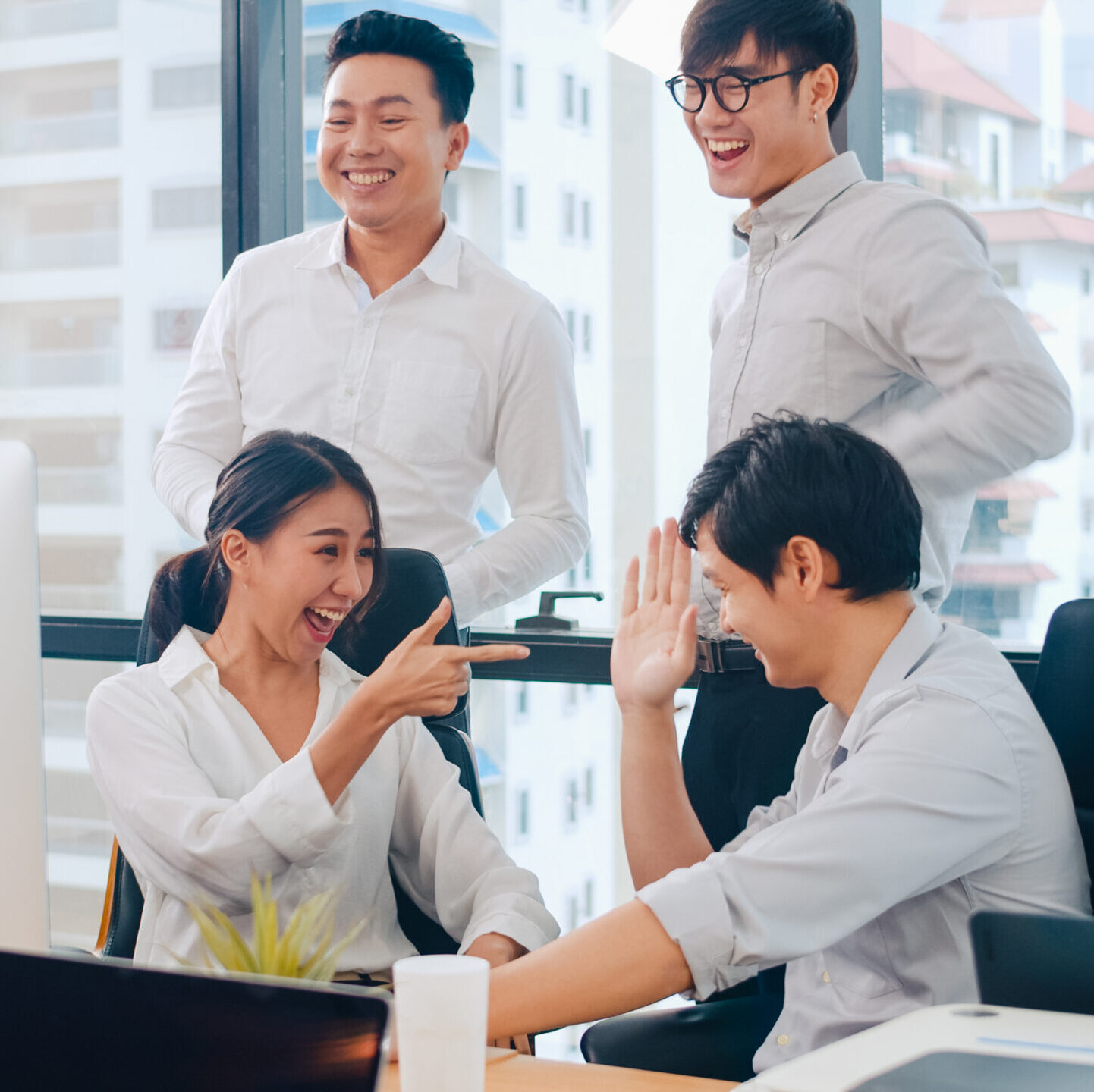 Millennial group of young businesspeople Asia businessman and businesswoman celebrate giving five after dealing feeling happy and signing contract or agreement at meeting room in small modern office.