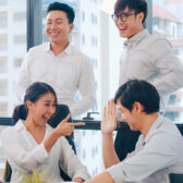 Millennial group of young businesspeople Asia businessman and businesswoman celebrate giving five after dealing feeling happy and signing contract or agreement at meeting room in small modern office.